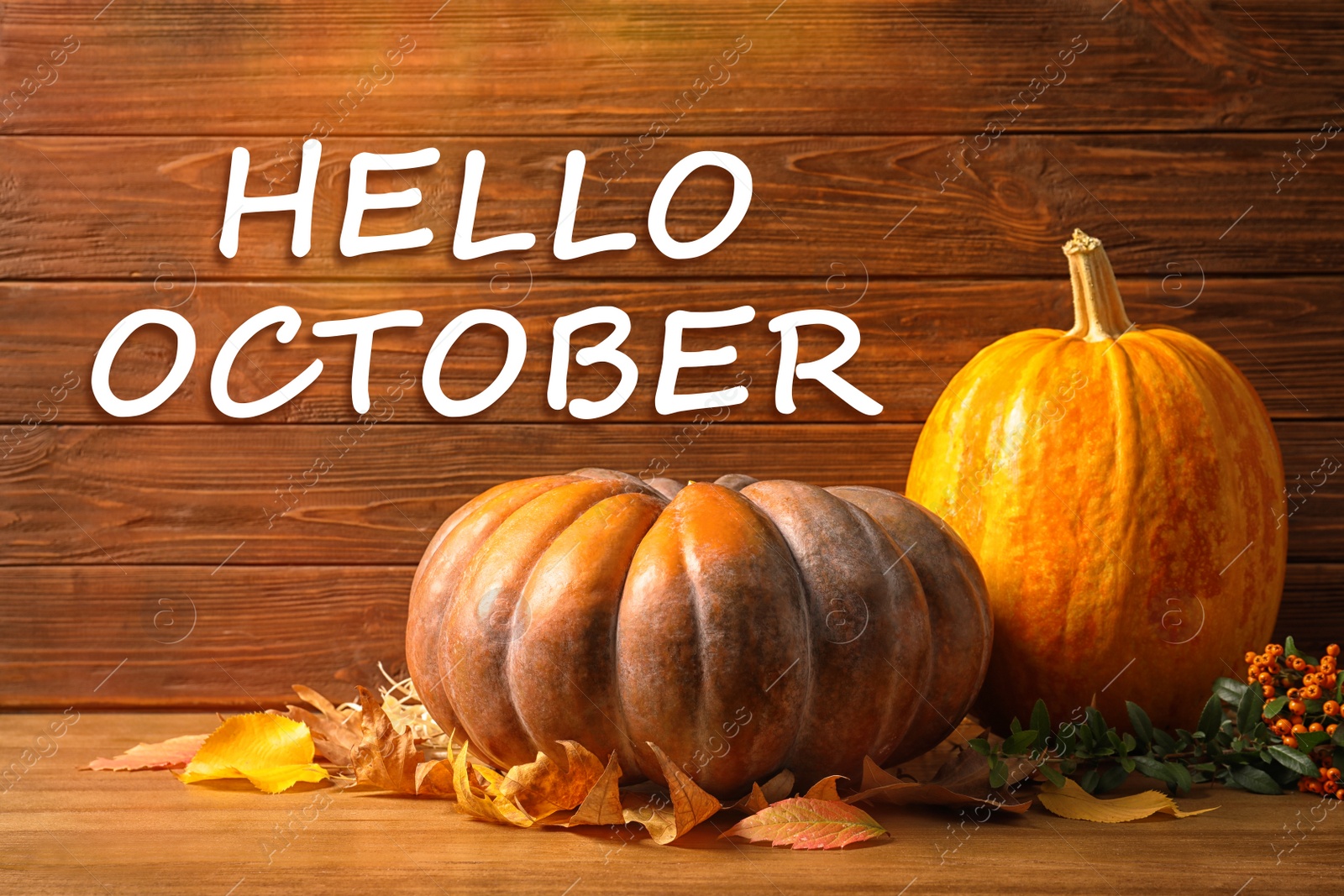 Image of Hello October card. Pumpkins and dry leaves on wooden table