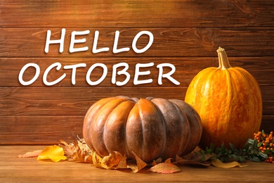 Hello October card. Pumpkins and dry leaves on wooden table