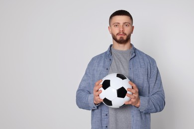 Photo of Athletic young man with soccer ball on light grey background. Space for text