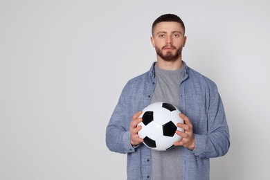 Athletic young man with soccer ball on light grey background. Space for text