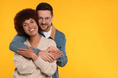 Photo of International dating. Happy couple hugging on orange background, space for text