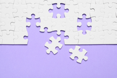 Photo of Blank white puzzle pieces on violet background, flat lay