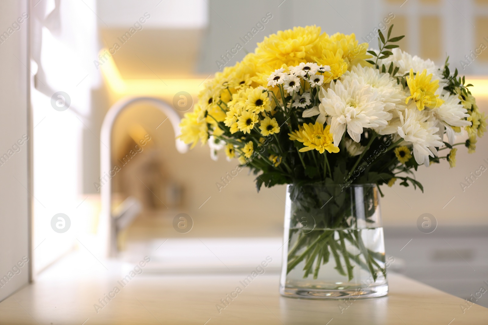 Photo of Vase with beautiful chrysanthemum flowers on countertop in kitchen, space for text. Interior design