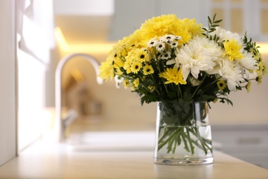 Vase with beautiful chrysanthemum flowers on countertop in kitchen, space for text. Interior design