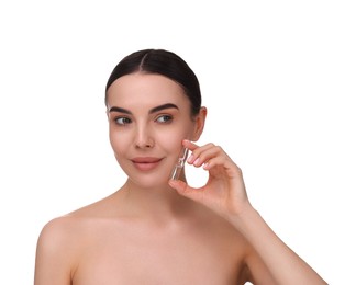 Beautiful young woman holding skincare ampoule on white background