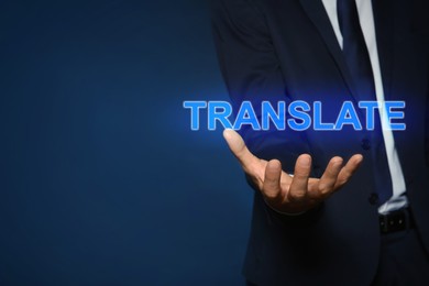 Image of Man showing virtual model of word TRANSLATE against dark blue background, closeup. Space for text