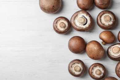 Photo of Fresh champignon mushrooms on wooden background, top view with space for text