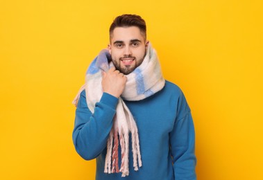 Smiling man in warm scarf on yellow background