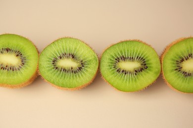 Photo of Halves of fresh kiwis on beige background, flat lay