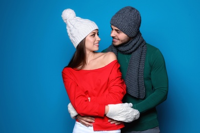 Photo of Young couple in warm clothes on color background. Christmas celebration