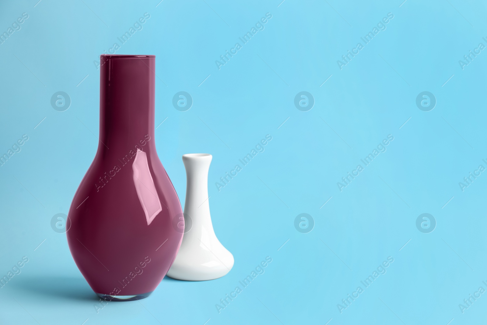 Photo of Stylish empty ceramic vases on light blue background, space for text