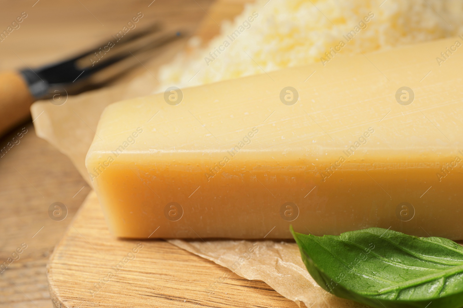 Photo of Delicious parmesan cheese and basil on wooden table, closeup