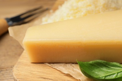 Photo of Delicious parmesan cheese and basil on wooden table, closeup