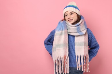 Photo of Beautiful woman in warm scarf and hat on pink background, space for text
