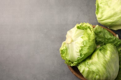Photo of Fresh green iceberg lettuce heads and leaves on grey table, flat lay. Space for text