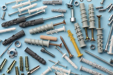 Photo of Many different fasteners and dowels on light blue background, flat lay