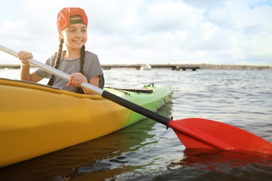 Photo of Happy little girl kayaking on river. Summer camp activity