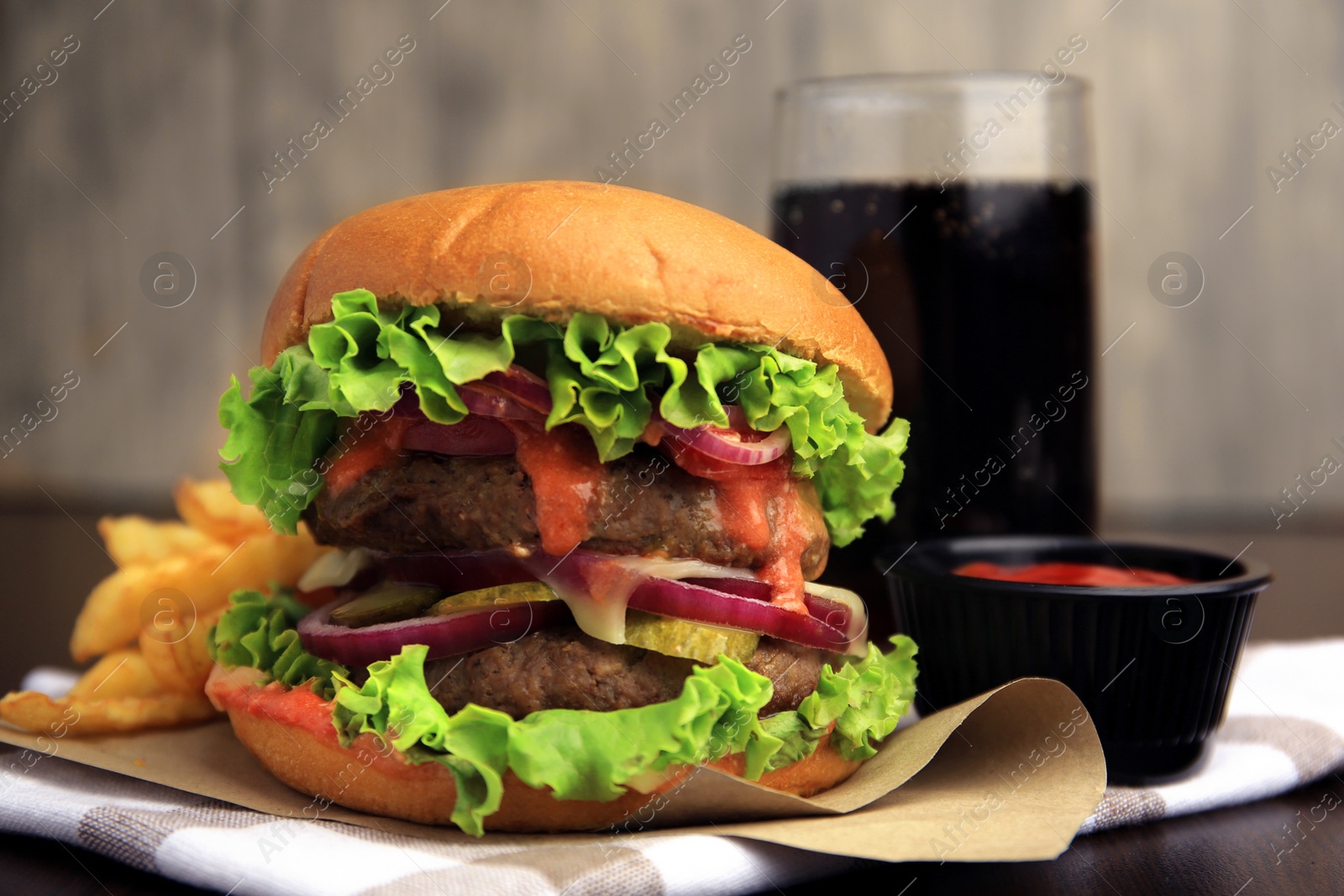 Photo of Tasty burger with vegetables, patties and lettuce served on wooden table, closeup