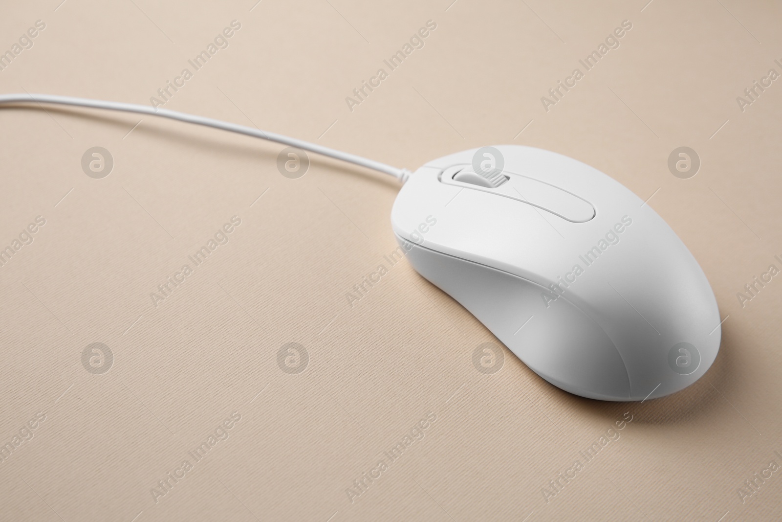 Photo of One wired mouse on beige background, closeup