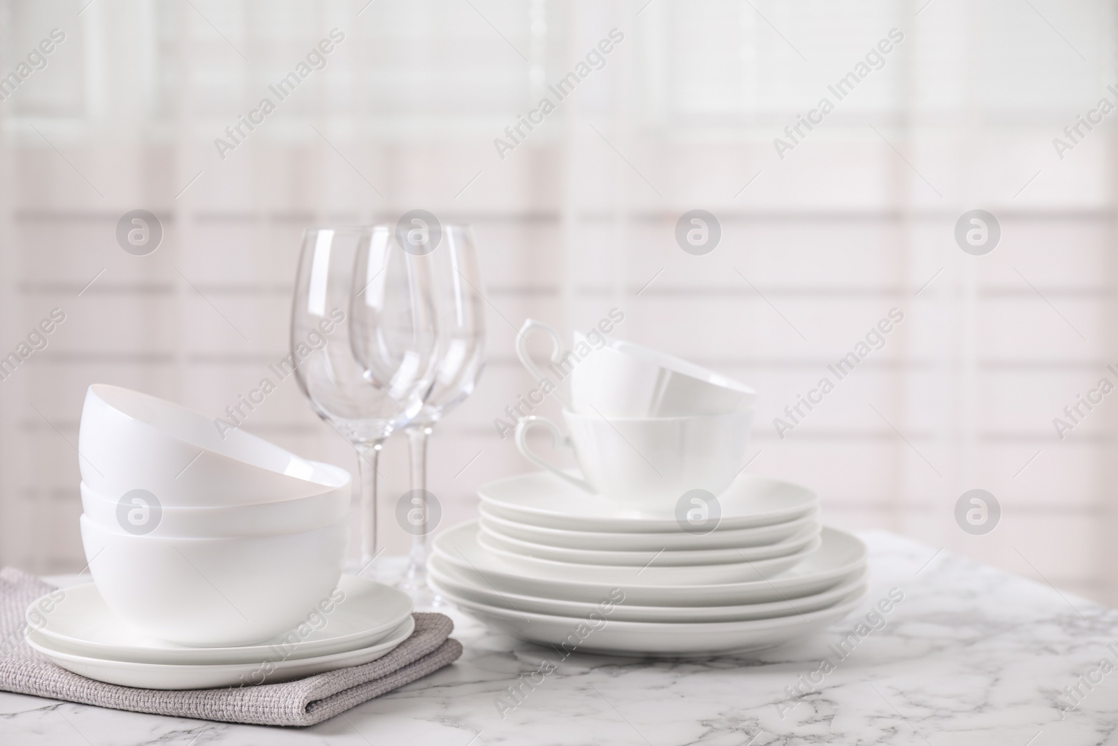 Photo of Set of clean tableware on white marble table