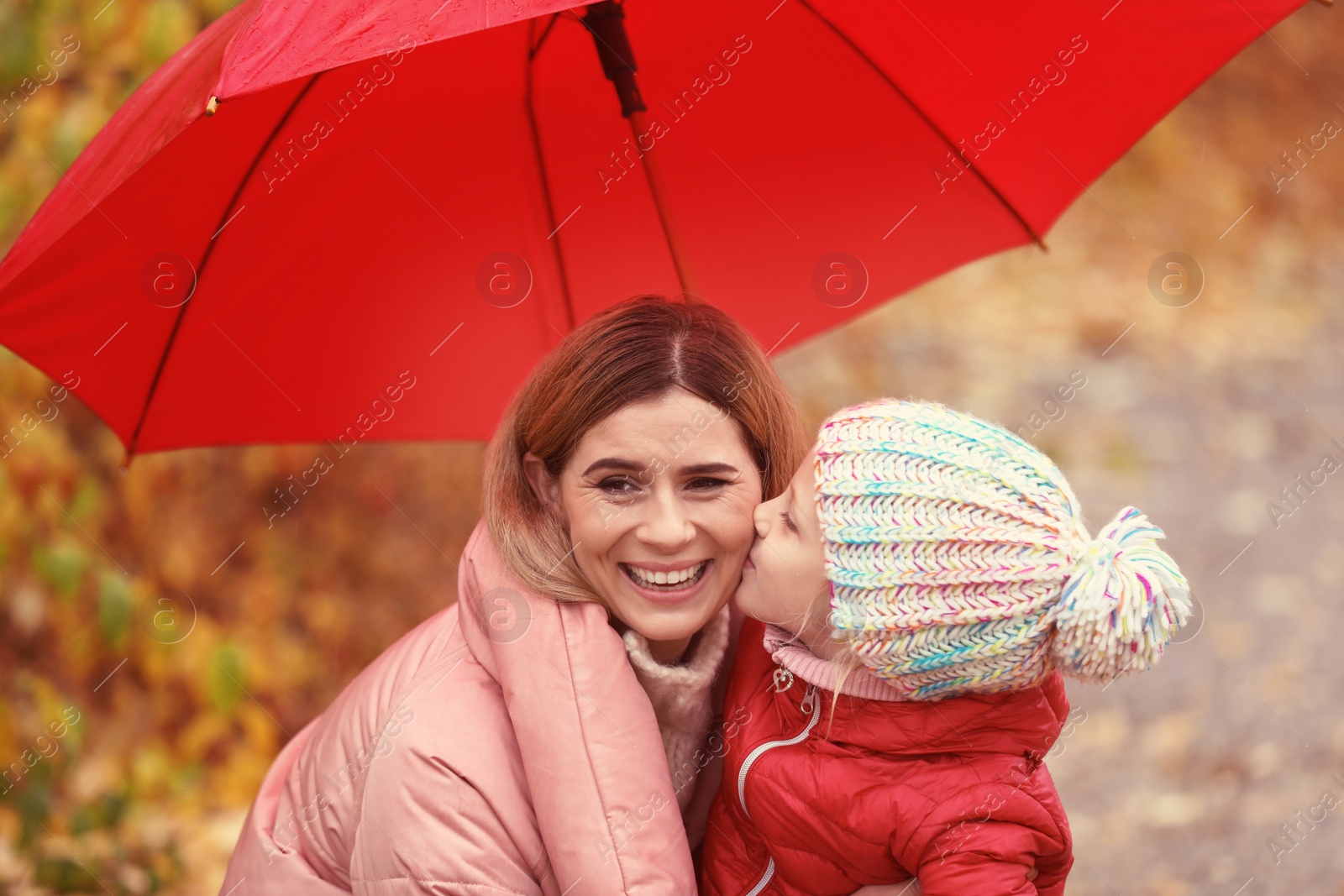 Photo of Mother and daughter with umbrella in autumn park on rainy day