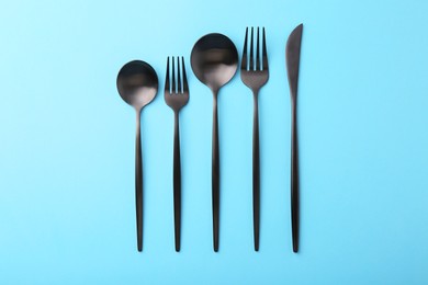 Photo of Stylish cutlery set on light blue table, flat lay