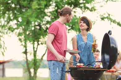 Photo of Young people having barbecue with modern grill outdoors