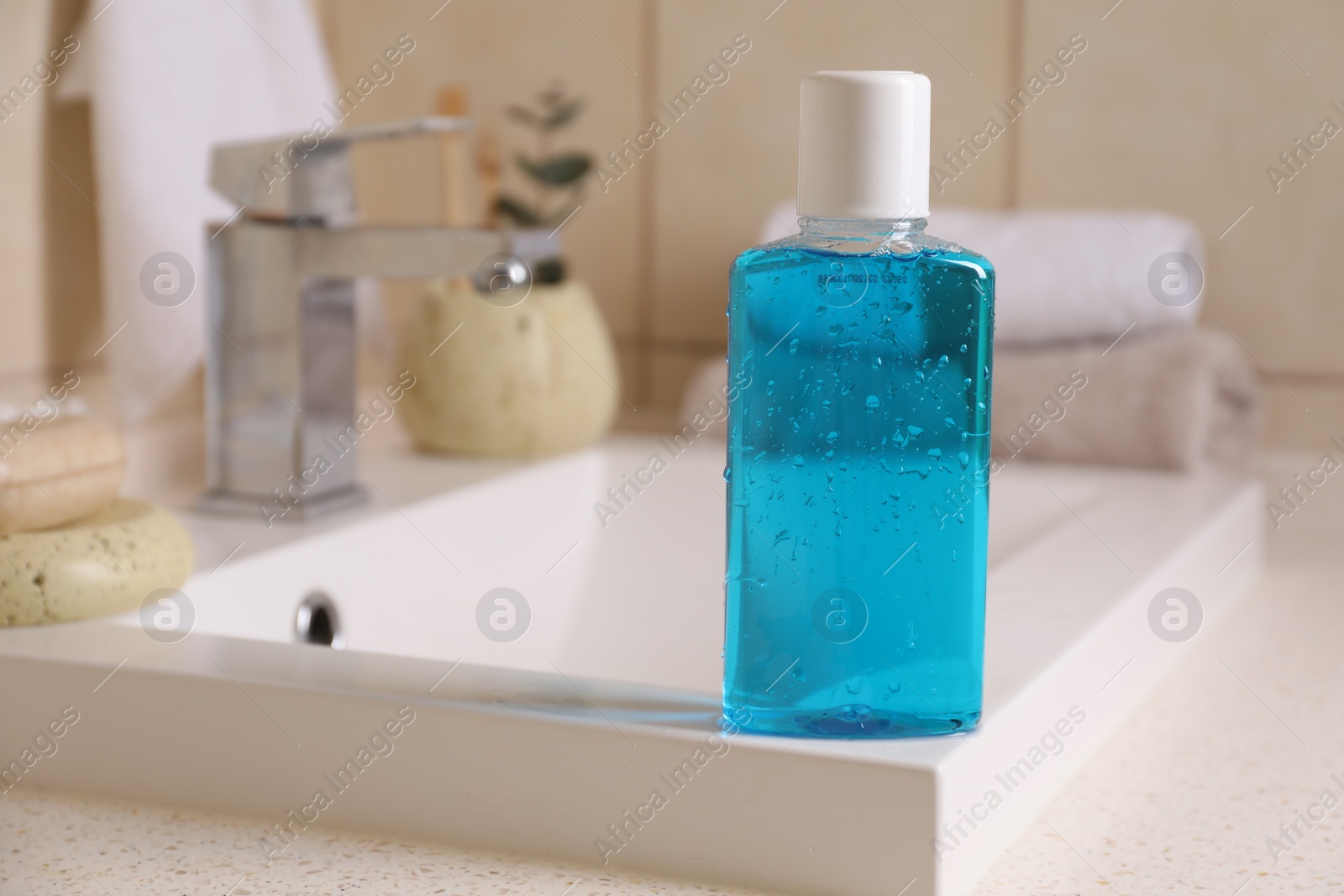 Photo of Fresh mouthwash in bottle on sink in bathroom, closeup. Space for text