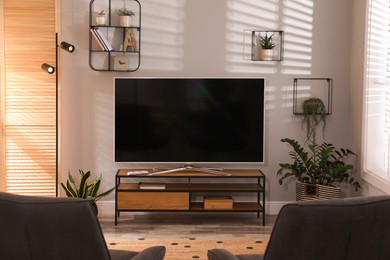Photo of Stylish living room interior with TV on cabinet and houseplants