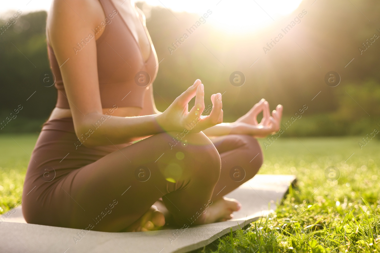 Photo of Woman practicing Padmasana on yoga mat outdoors, closeup. Lotus pose