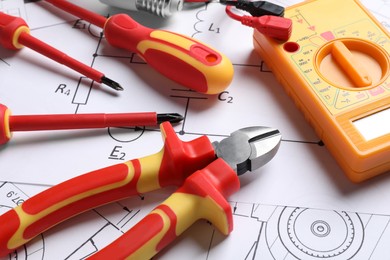 Photo of Set of electrician's tools and accessories on paper sheets, closeup