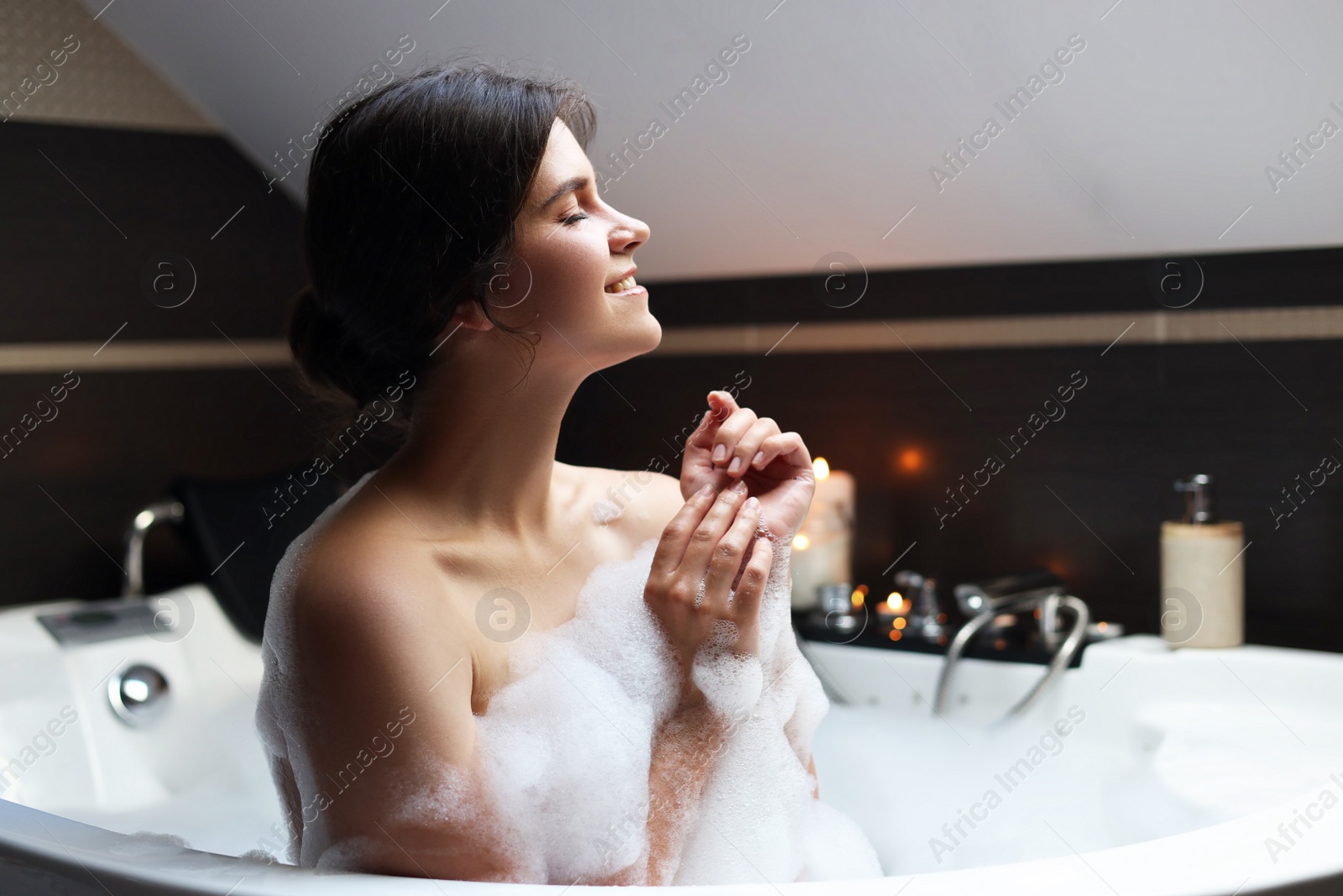 Photo of Happy beautiful woman taking bubble bath. Romantic atmosphere