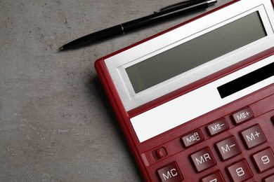 Calculator and pen on grey table, flat lay