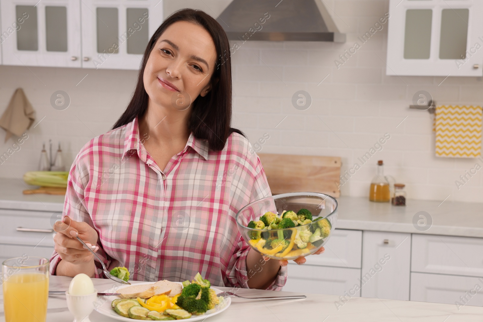 Photo of Beautiful overweight woman having healthy meal at table in kitchen