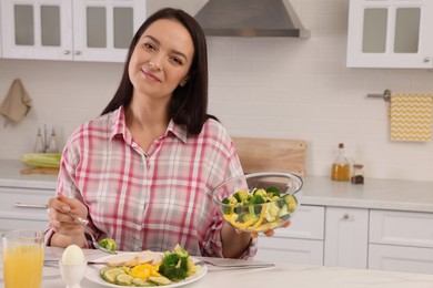 Beautiful overweight woman having healthy meal at table in kitchen