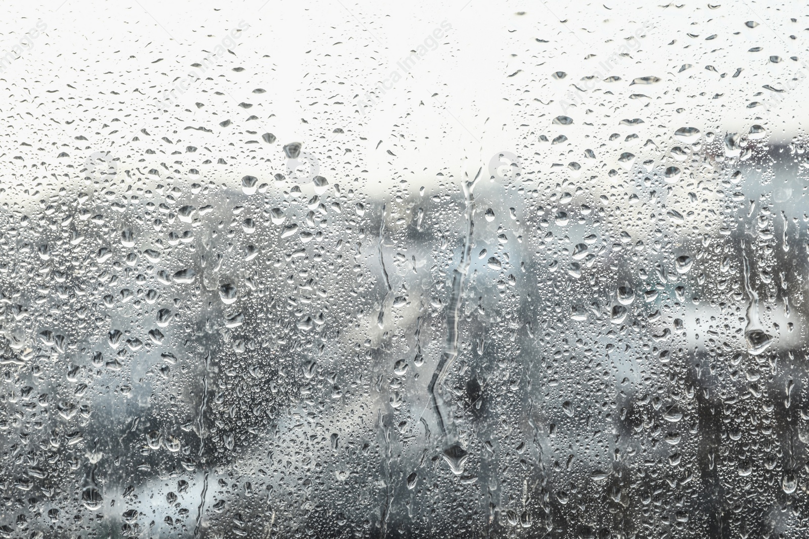 Photo of Blurred view of city from window on rainy day