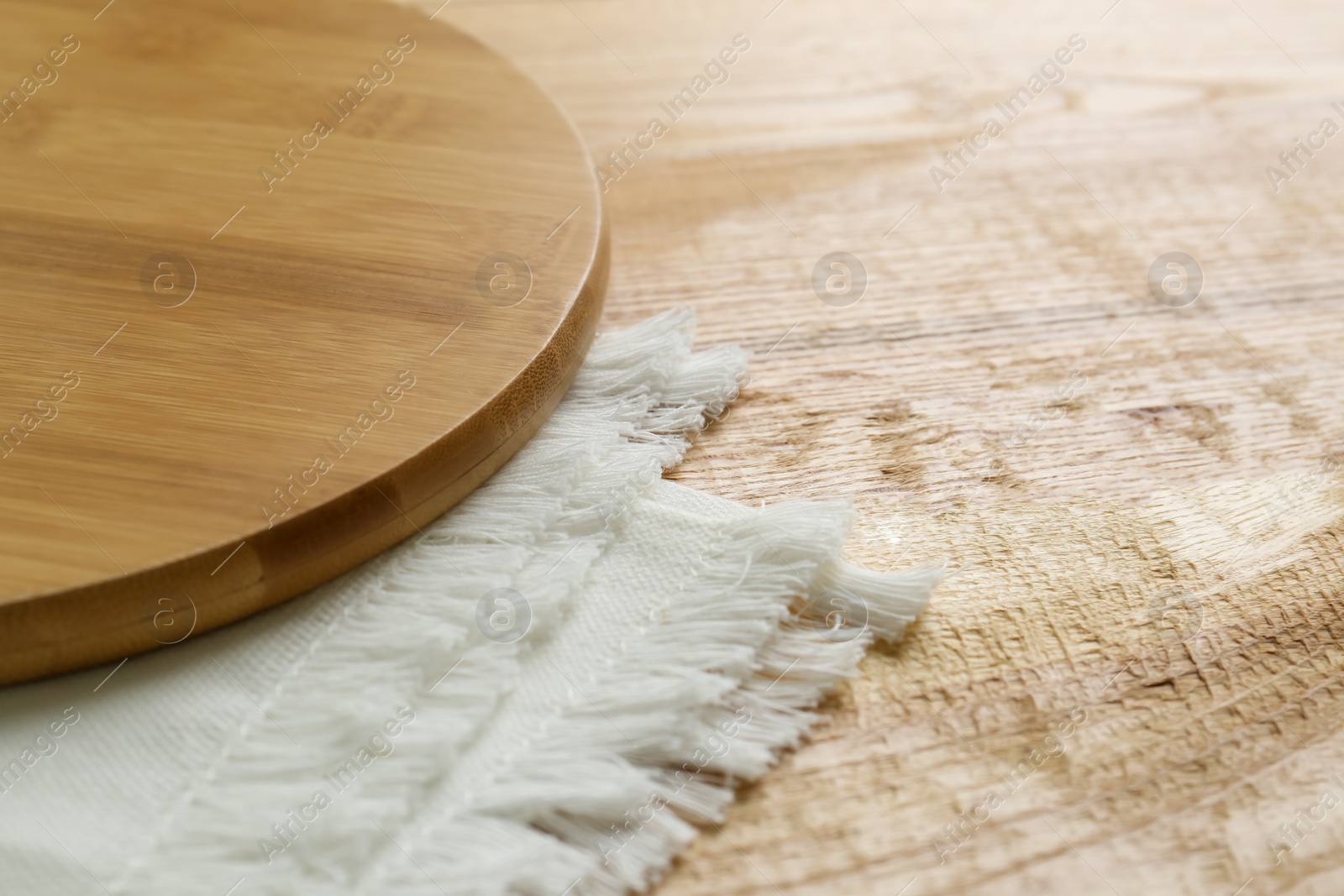 Photo of Empty wooden board and napkin on table, closeup. Space for text