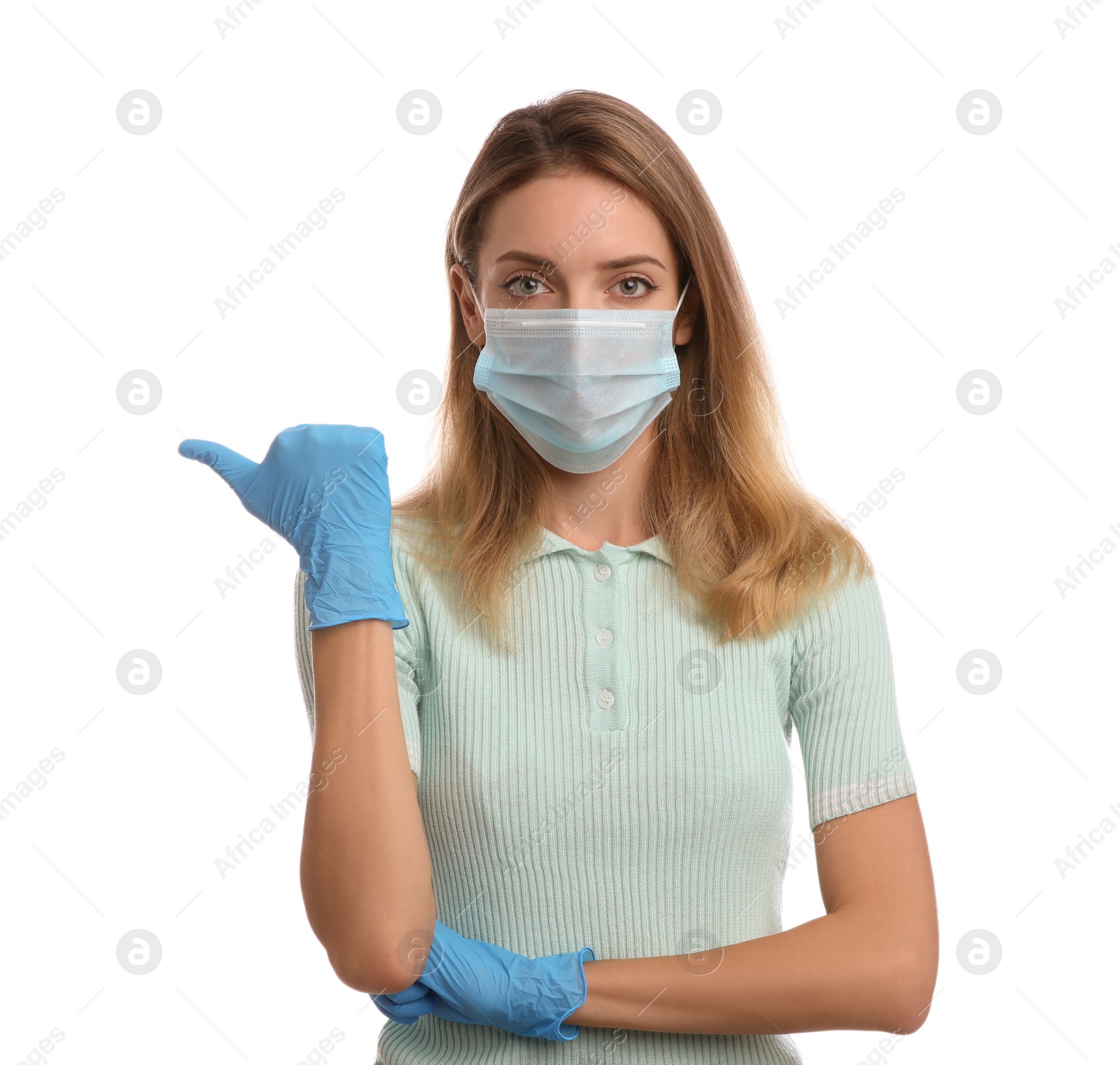 Photo of Young woman in medical gloves and protective mask pointing thumb aside on white background
