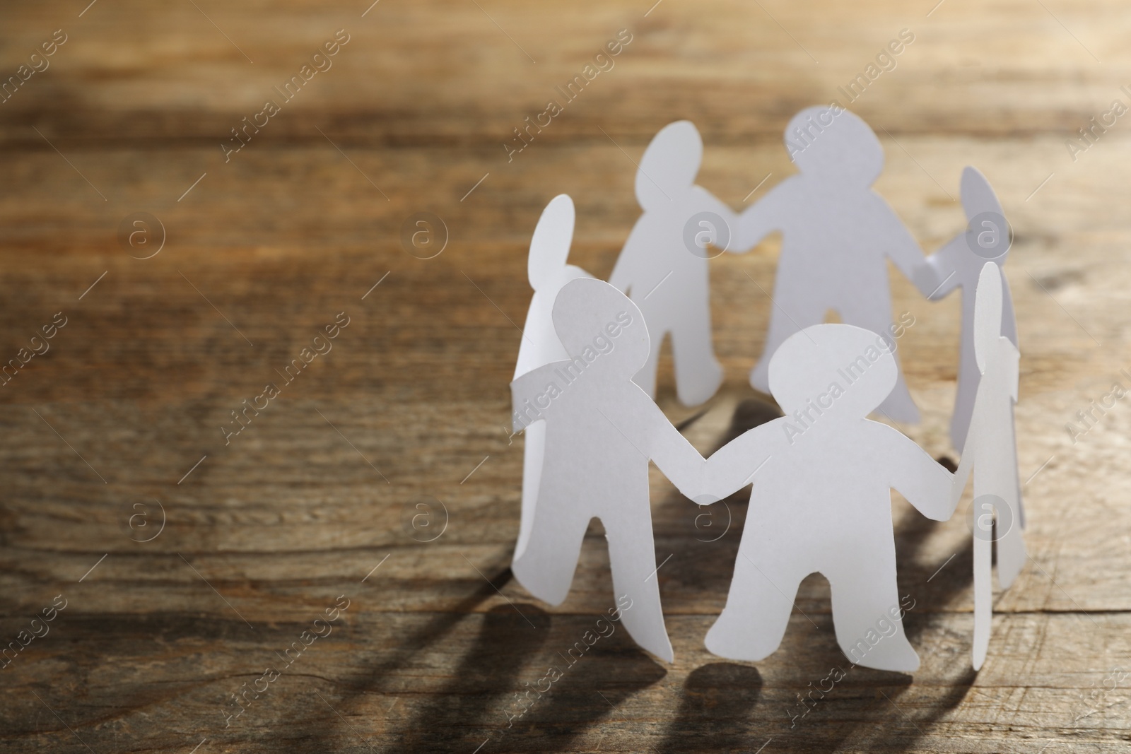 Photo of Paper people chain making circle on wooden background, space for text. Unity concept