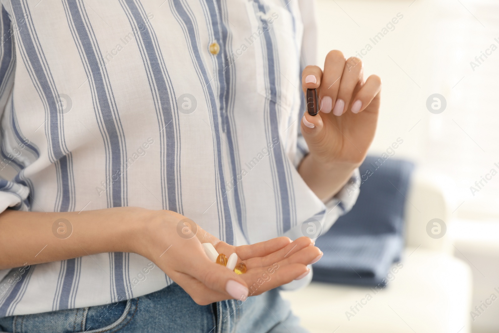 Photo of Young woman with vitamins on light background, closeup