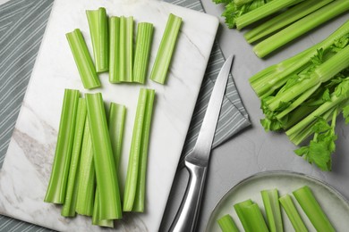 Fresh green celery and knife on light grey table, flat lay