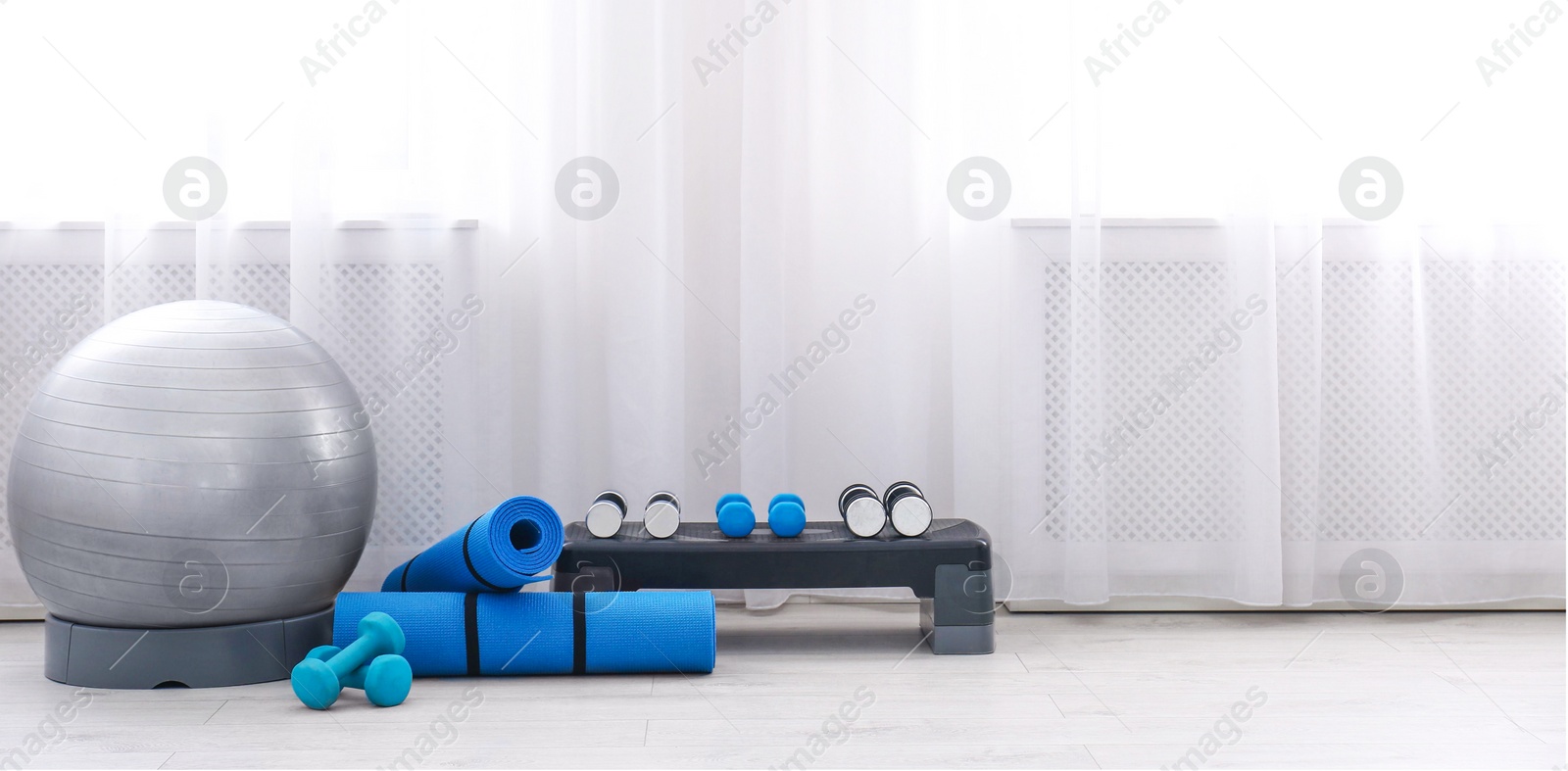 Photo of Different sports equipment near window in gym. Space for text