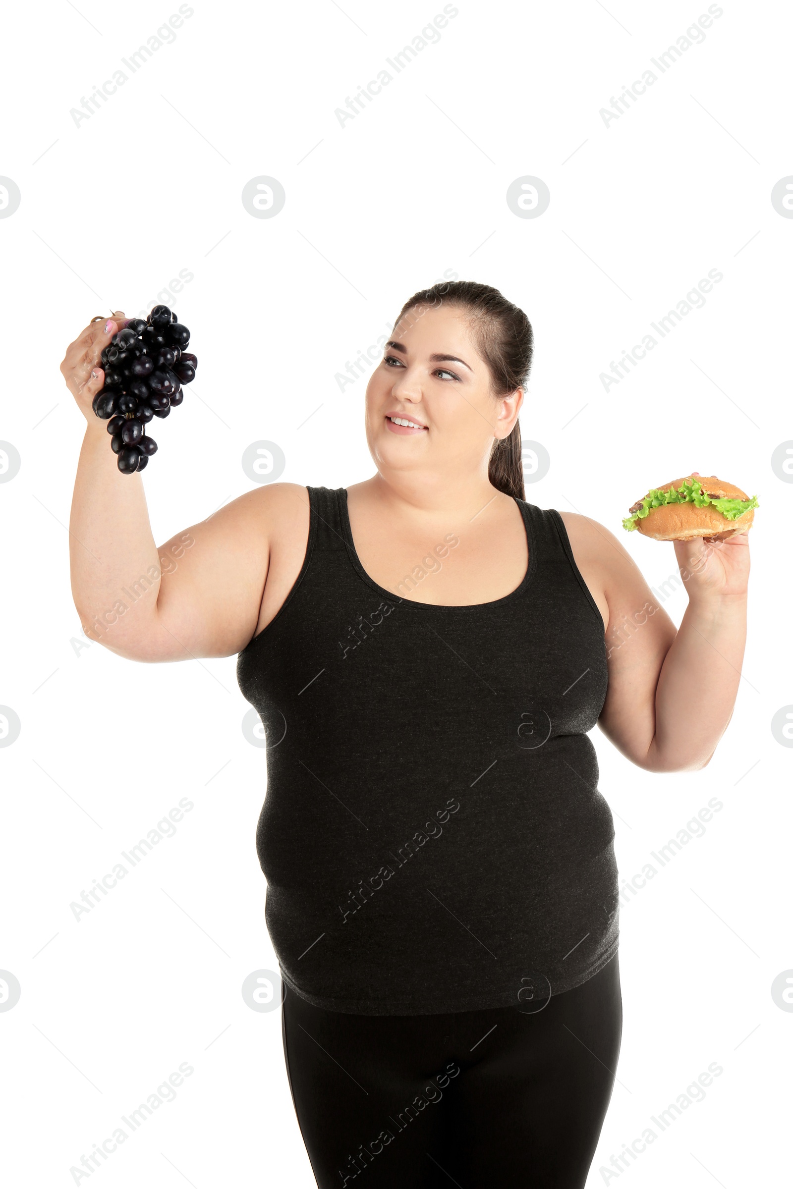 Photo of Overweight woman with hamburger and grapes on white background