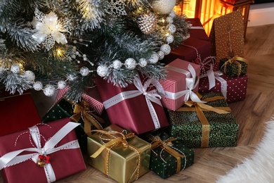 Photo of Pile of gift boxes near beautiful Christmas tree indoors