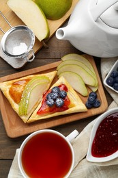 Photo of Fresh tasty puff pastry with jam, blueberries and pear served on wooden table, flat lay
