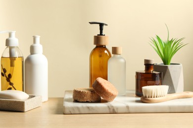 Photo of Different bath accessories and houseplant on wooden table against beige background