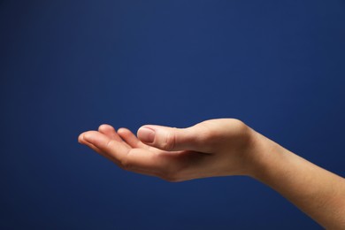 Woman holding something in hand on blue background, closeup. Space for text