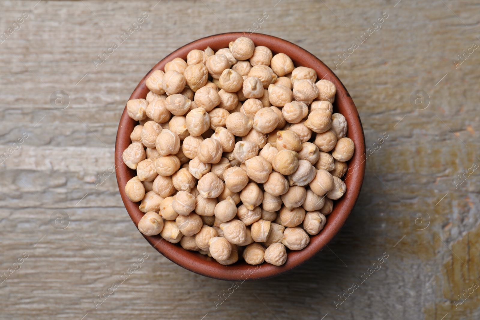 Photo of Chickpeas in bowl on wooden table, top view