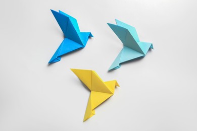 Photo of Beautiful colorful origami birds on white background, flat lay