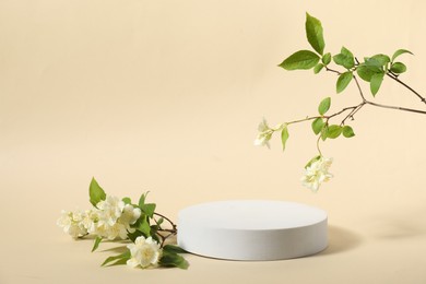 Photo of Presentation of product. White podium and beautiful jasmine flowers on beige background, space for text